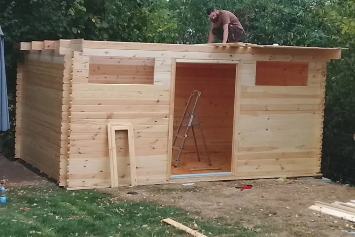 Monteur verlegt die Dachschalung des Gartenhauses