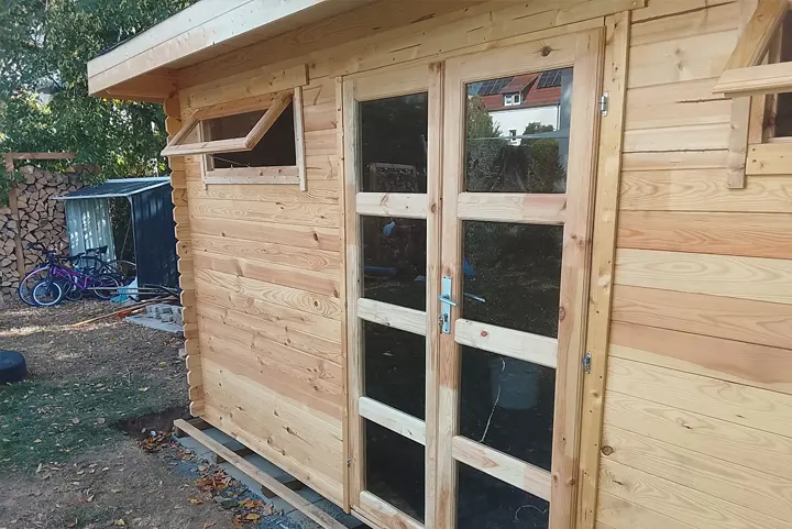 Eingebaute Glastür und Kippfenster in der Seitenwand des Gartenhauses