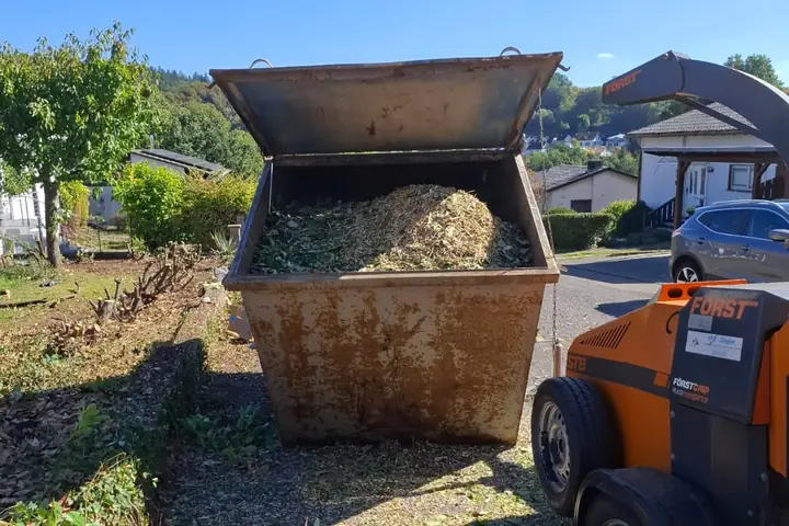 Container mit gehäckseltem Schnittgut neben dem Häcksler